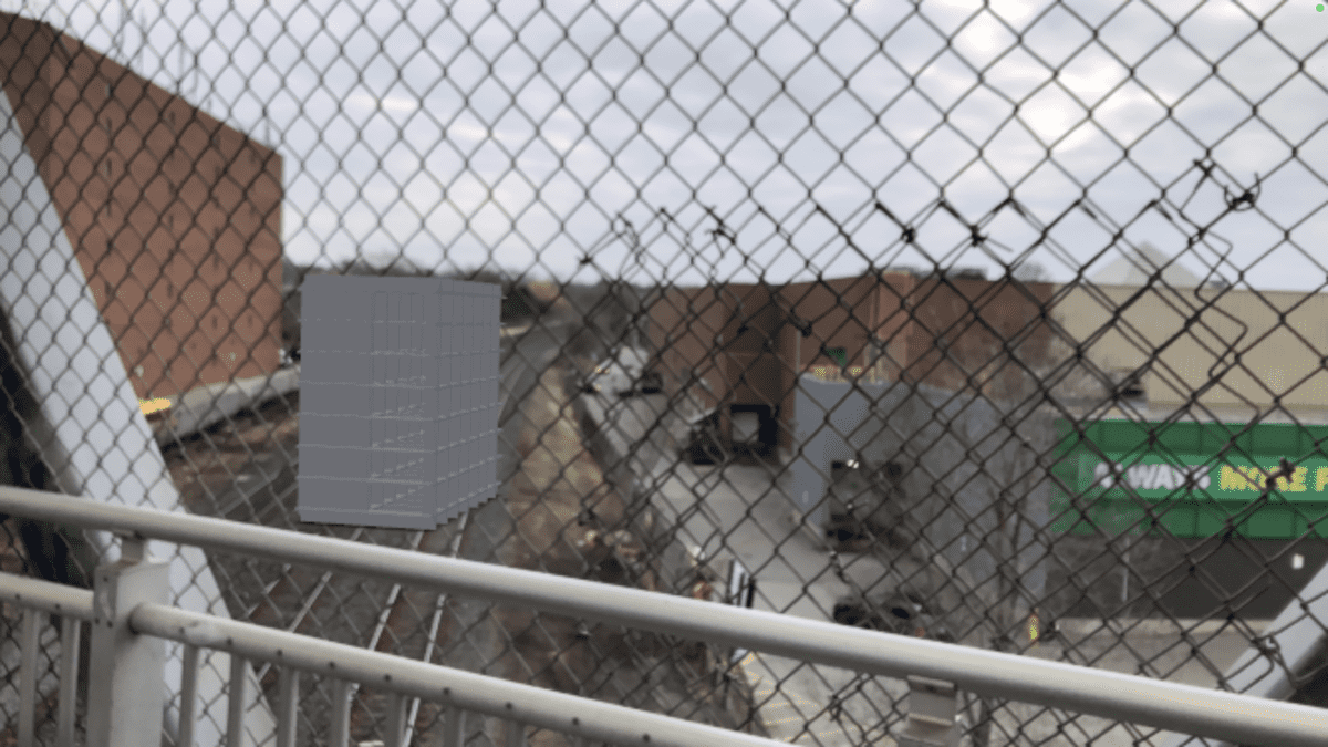 an animated grey box through a chain link fence